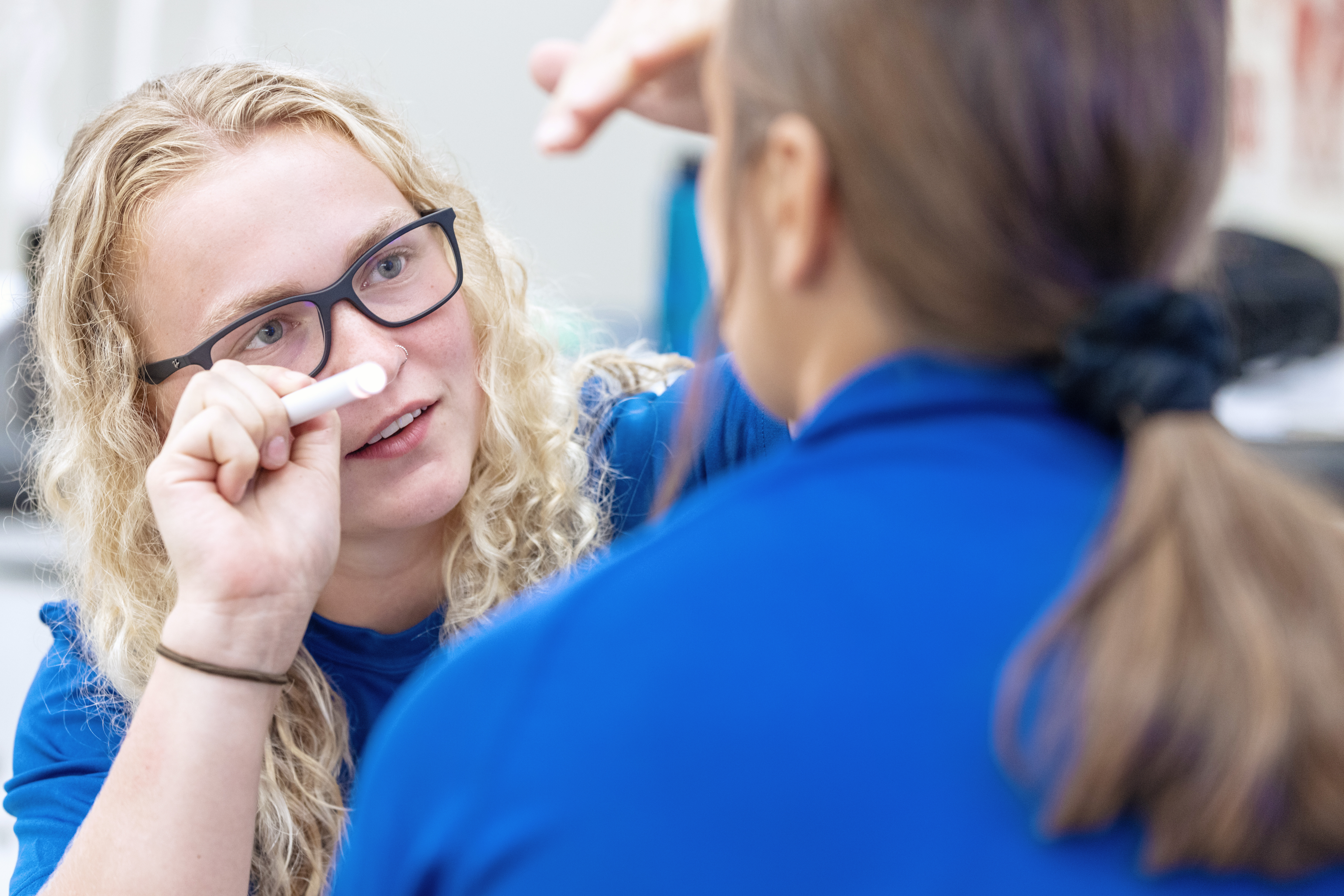 Master of Athletic Training student performing practice eye exam on fellow student.