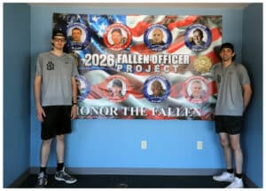 Zach Kowalewicz (right) poses with a banner that honors the first responders in the 2026 Fallen Officer Project. Kowalewicz connected with the family of Chevy Gall, a firefighter who passed away in April 2025. 